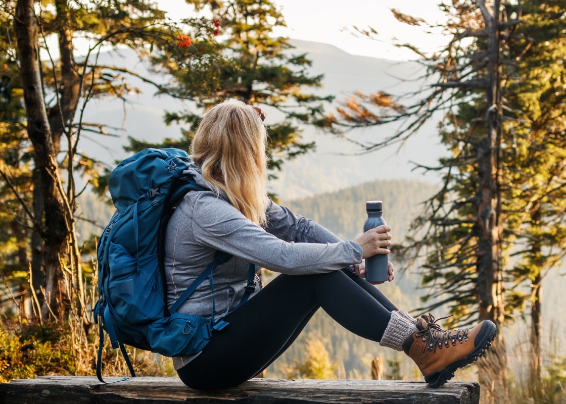 Person with branded backpack and water bottle enjoying autumn day