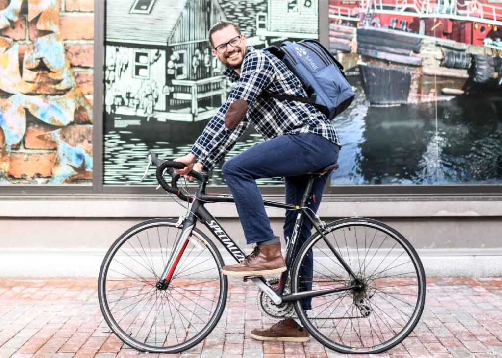 Cyclist on bike, wearing branded backpack.